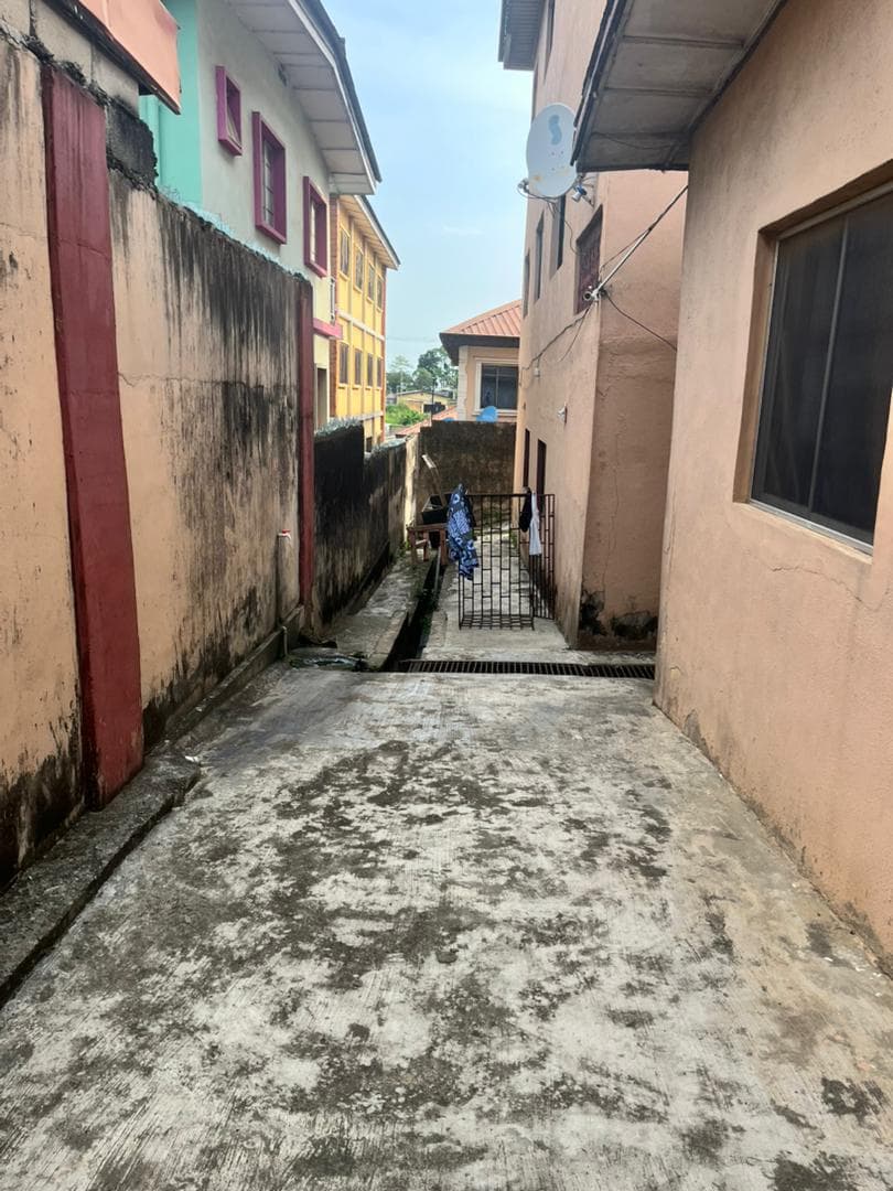 An open drainage channel running along the rear passage of the compound.